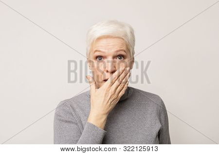 No Way. Shocked Senior Woman With Widely Opened Eyes Covering Her Mouth With Hand Over Light Backgro