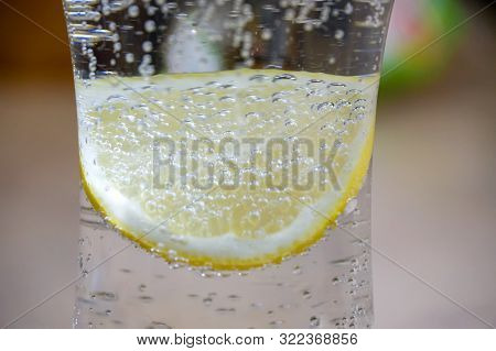 A Glass Of Fresh Drinking Water And Lemon. Bubbles In A Glass Mineral Water As A Thirst Quencher.