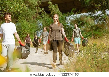 Team Of Building The Future. Group Of Volunteers Tidying Up Rubbish On Beach In Sunny Day. Young Men