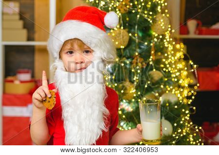 Santa Boy In Santa Hat. Funny Child Christmas. Santa Claus - Bearded Funny Child. Happy Santa Claus 