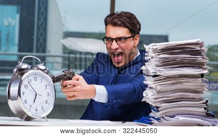 Businessman with pile stack of paper paperwork and an alarm cloc
