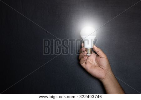 Manhand With Light Bulbs And Abstract Ideas On The Background Of A Dark Wall