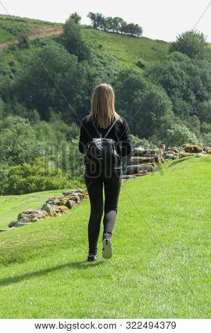 Hexham, Uk - Circa August 2015: Unidentified Girl Dressed In Black Walking On The Grass