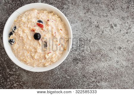 Top View Of Cereal Bowl Filled With Bircher Muesli With Blueberries And Cranberries On Stone Kitchen