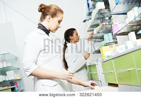 Two female pharmacutical chemists work at drugstore