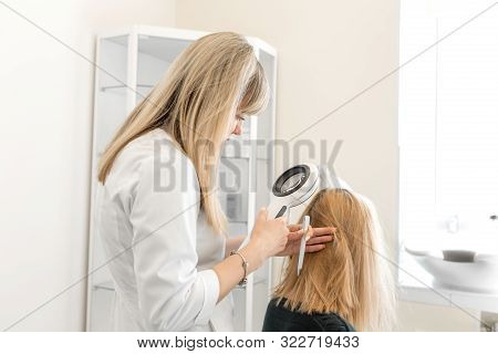 The Doctor Trichologist Dermatologist Examines The Scalp And The Patient's Hair Condition With A Der