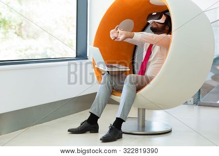 Businessman Testing Vr Simulator In Studio. Man In Office Clothes And Vr Headset Sitting In Interact