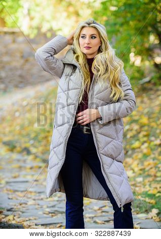Puffer Fashion Trend Concept. Girl Fashionable Blonde Walk In Autumn Park. Woman Wear Warm Grey Jack