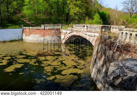 Old Arched Brick Bridge Across A Pond In Sharovka Palace Park In In Kharkov Region, Ukraine