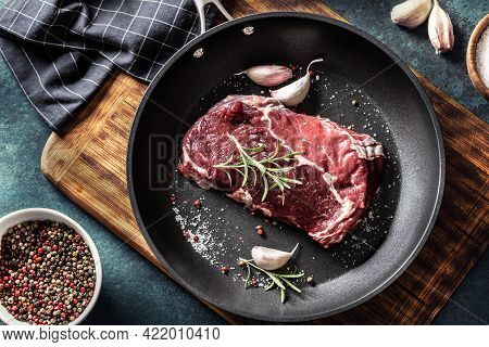 Fresh Raw Beef Ribe Eye Steak In Teflon Pan With Rosemary, Garlic, Salt And Pepper.