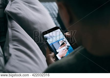 closeup of a young caucasian man, lying down at home, searching job online with his smartphone, with a simulated search engine in its screen that reads job search