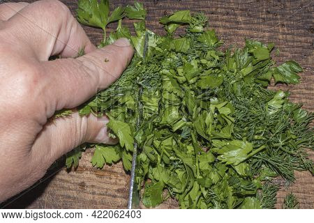 Slicing Parsley And Dill On A Wooden Board