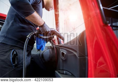 Car Service Worker Cleans Interiror With Steam Cleaner