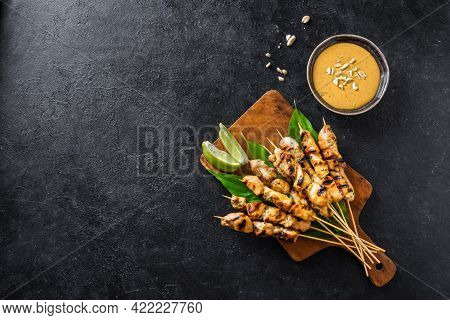 Chicken Grilled Satay Skewers Served With Lime And Peanut Sauce On Black, Copy Space. Asian Thai Sty