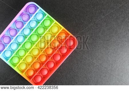 Toy Anti-stress Popit Simlpe Dimple Rainbow On A Black Background View From Top With Space For Text