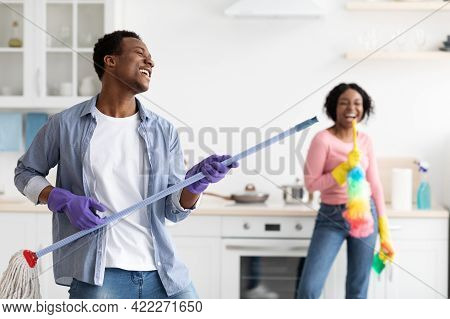 Playful Black Guy Imitating Rockstar While House-keeping