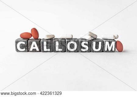 Callosum The Word On Stone Cubes. Cubes Stand On A White Surface, Many White And Red Pills. Medicine