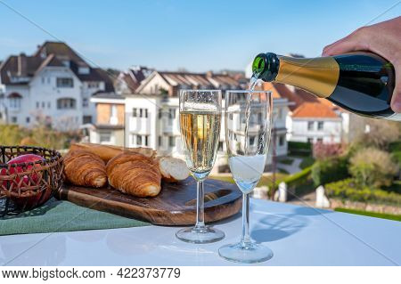 Pouring Of Brut Champagne Sparkling Wine In Flute Glasses On Outdoor Terrace In France