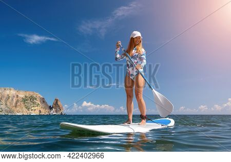 Healthy Happy Fit Woman In Bikini Relaxing On A Sup Surfboard, Floating On The Clear Turquoise Sea W