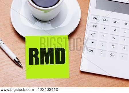 The Wooden Table Has A White Cup Of Coffee, A Pen, A White Calculator, And A Green Sticker With The 