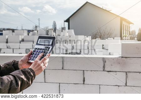 Calculation Of Building Materials. Woman Calculates Cost Of Building House. Calculator On Background
