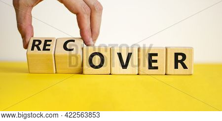 Time To Recover Symbol. Businessman Turns Wooden Cubes And Changes The Word 'over' To 'recover'. Bea