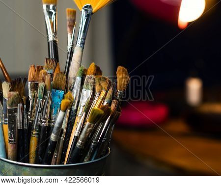 Set Collection Art Paint Brushes In Cup On Artists Desktop. Artistic Equipment In Studio