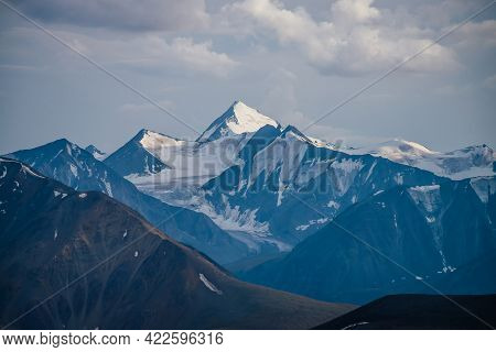 Awesome Mountains Landscape With Big Snowy Mountain Pinnacle In Blue White Colors Under Cloudy Sky. 