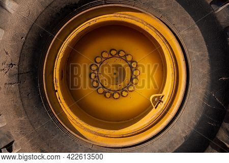 Close-up Of A Large Yellow Wheel Rim With An Old Tire And Large Bolts. Loader Wheel. Tire Service.