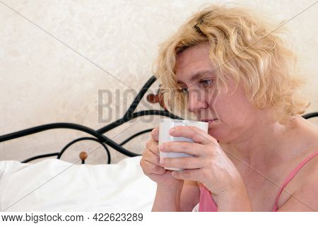 A Woman After Waking Up From Sleep Holds A Cup Of Coffee Or Tea In Her Hands.