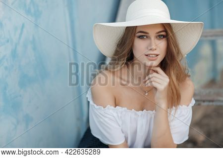 A Beautiful Young Woman With Long Blond Hair, Gray Eyes, Clean Skin And Pink Lips In A Straw Hat Loo
