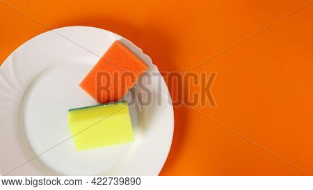 2 Dish Sponge On White Plate And Orange Background With Copy Space