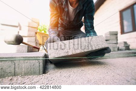 Worker lining paving slabs path