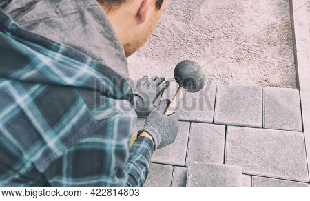 Worker lining paving slabs path