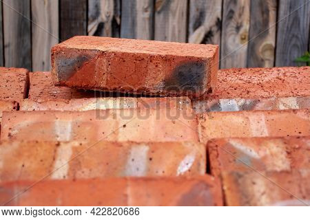 Fireclay Red Brick Lies On A Pallet Of Bricks Against Background Of Boards. Selective Focus On The B