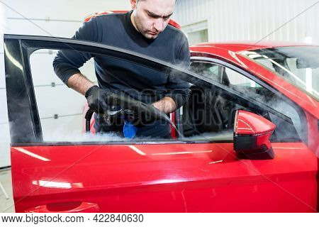 Car Service Worker Cleans Interiror With Steam Cleaner