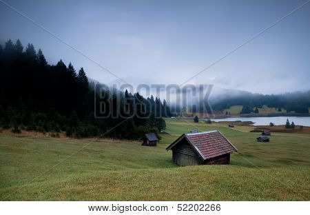 Wooden Huts And Fog Over Geroldsee Lake In Dusk