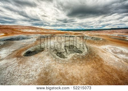 Mudpots in the geothermal area Hverir, Iceland. The area around the boiling mud is multicolored and cracked. HDR image