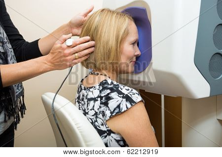 Midsection of female optometrist adjusting patient's head for retinal checkup