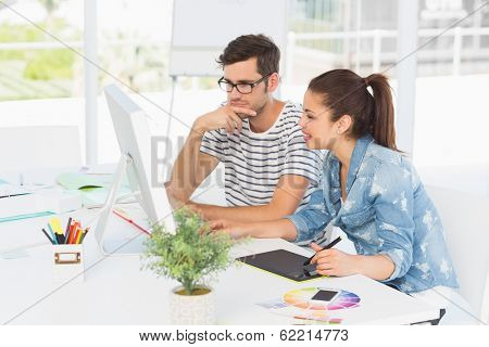 Side view of casual photo editors using graphics tablet in the office