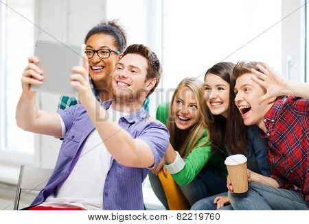 education and technology - group of students taking selfie with tablet pc at school