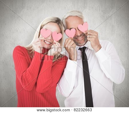 Silly couple holding hearts over their eyes against weathered surface