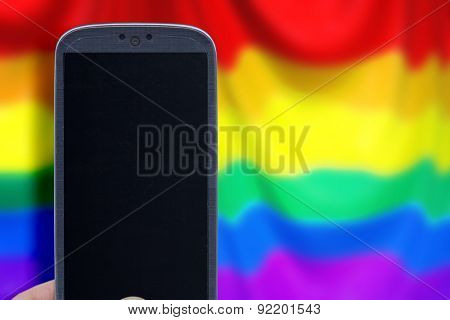 Blue smartphone and LGBT flag blur background. Idea for Valentines Day messages, LGBT love, lovers, love apps, Internet, blogs and others.