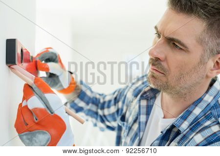 Mid-adult man marking on wall with level