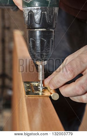 Door installation Woodworker install door butt hinges using a screw gun drill driver close-up.
