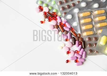 View on scattered pills and tablets in packeges on white background.From above