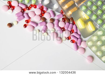 View on scattered pills and tablets in packeges on white background.From above
