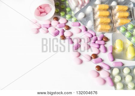 View on scattered pills and tablets in packeges on white background.From above