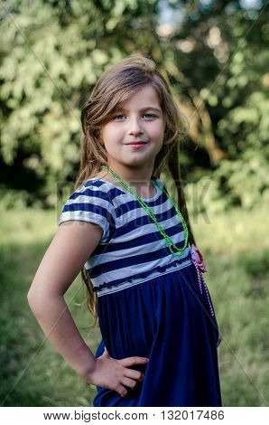 Lovely little girl with long brown hair and blue eyes. Good Posing. Summer portrait.