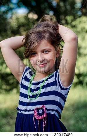 Lovely little girl with long brown hair and blue eyes. Good Posing. Summer portrait.